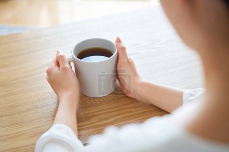 Photo for A woman's hand holding a mug and thinking in the room - Royalty Free Image