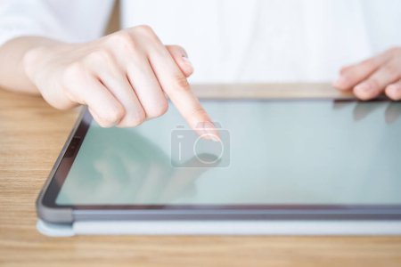 Téléchargez les photos : La main d'une femme qui touche et actionne l'écran d'une tablette PC - en image libre de droit