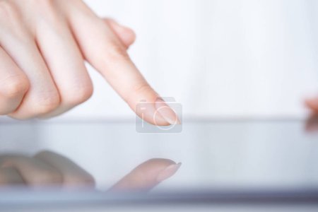 Téléchargez les photos : La main d'une femme qui touche et actionne l'écran d'une tablette PC - en image libre de droit