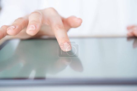 Foto de La mano de una mujer que toca y opera la pantalla de una tableta - Imagen libre de derechos