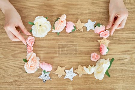 Foto de Manos de mujer haciendo un marco con accesorios en forma de flor y estrella - Imagen libre de derechos