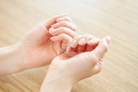 Photo for A woman's hand checking the condition of her nails - Royalty Free Image