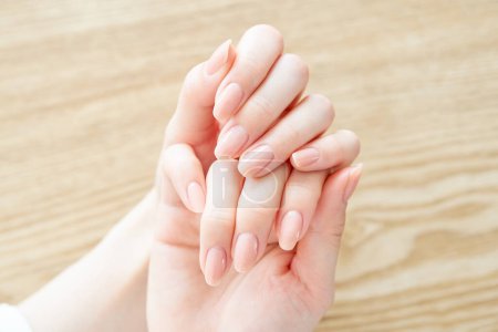 Photo for A woman's hand checking the condition of her nails - Royalty Free Image