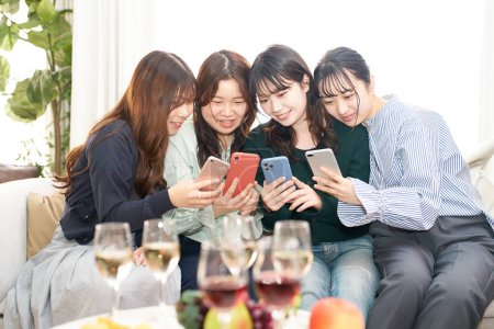 Téléchargez les photos : Quatre femmes parlent en regardant leurs smartphones à l'intérieur - en image libre de droit