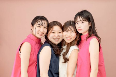 Téléchargez les photos : Un groupe de quatre jeunes femmes debout devant un fond de couleur - en image libre de droit