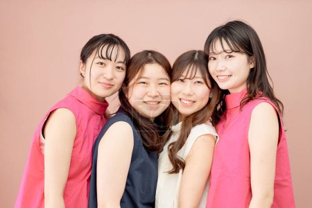 Téléchargez les photos : Un groupe de quatre jeunes femmes debout devant un fond de couleur - en image libre de droit