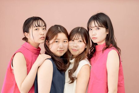 Foto de Un grupo de cuatro mujeres jóvenes de pie frente a un fondo de color - Imagen libre de derechos
