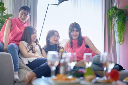 Foto de Cuatro mujeres jóvenes relajándose en una fiesta en casa - Imagen libre de derechos
