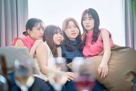 Téléchargez les photos : Quatre jeunes femmes se relaxant à une fête à la maison - en image libre de droit