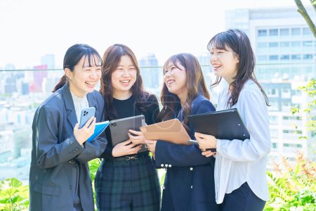 Téléchargez les photos : Quatre jeunes femmes d'affaires bavardant dehors par une journée ensoleillée - en image libre de droit