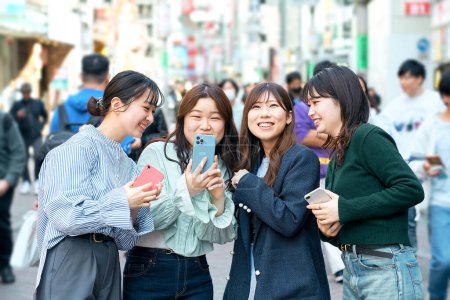 Photo for Young women happily using smartphones in the city - Royalty Free Image