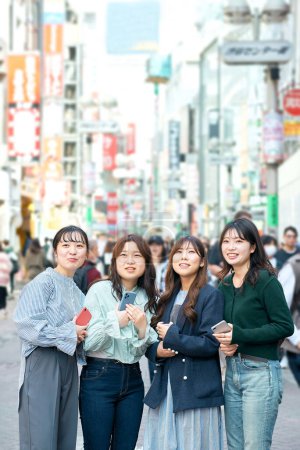 Téléchargez les photos : Les jeunes femmes utilisent joyeusement les smartphones dans la ville - en image libre de droit
