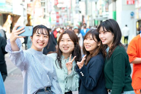 Photo for Four women happily taking selfies in the city - Royalty Free Image