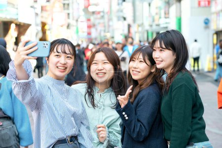 Téléchargez les photos : Quatre femmes prennent volontiers des selfies dans la ville - en image libre de droit