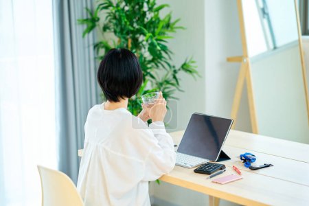 Téléchargez les photos : Une femme qui fait une pause en travaillant sur un ordinateur dans sa chambre - en image libre de droit