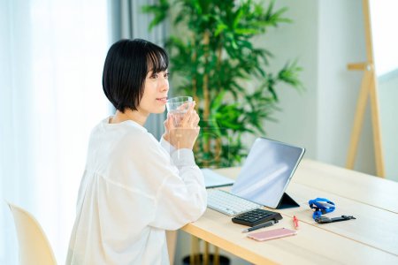 Photo for A woman taking a break while working on a computer in her room - Royalty Free Image