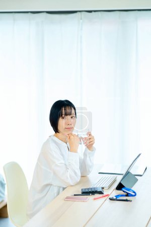 Photo for A woman taking a break while working on a computer in her room - Royalty Free Image