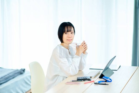 Téléchargez les photos : Une femme qui fait une pause en travaillant sur un ordinateur dans sa chambre - en image libre de droit
