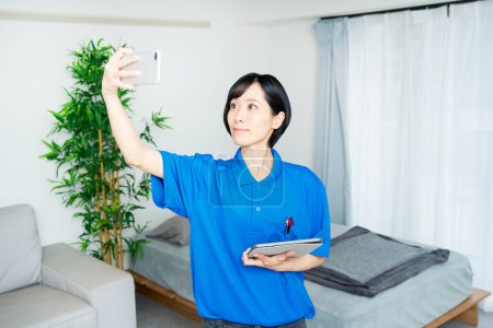 Foto de Una mujer en ropa de trabajo revisando el estado de la habitación - Imagen libre de derechos
