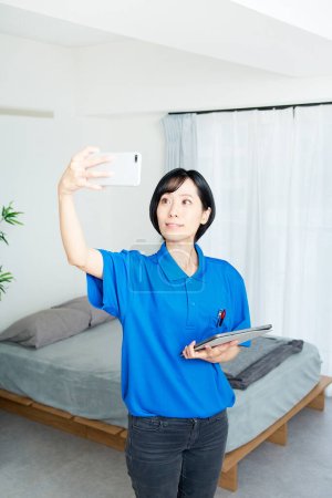 Foto de Una mujer en ropa de trabajo revisando el estado de la habitación - Imagen libre de derechos