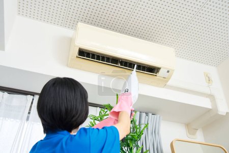 Téléchargez les photos : Une femme en vêtements de travail nettoie le climatiseur - en image libre de droit
