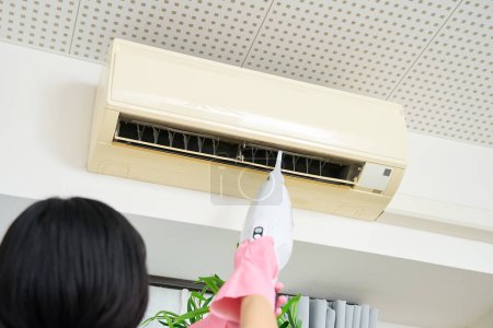Photo for A woman in work clothes cleaning the air conditioner - Royalty Free Image