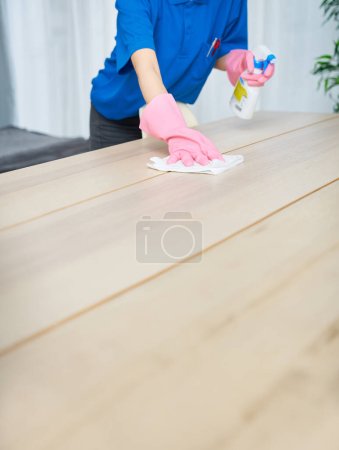 Foto de Una mujer con ropa de trabajo y máscara limpiando la habitación - Imagen libre de derechos