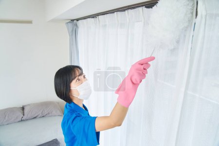 Foto de Una mujer con ropa de trabajo limpiando la habitación - Imagen libre de derechos