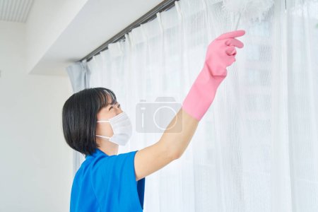 Foto de Una mujer con ropa de trabajo limpiando la habitación - Imagen libre de derechos
