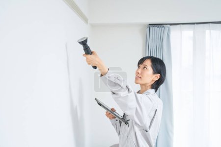 Foto de Una mujer en ropa de trabajo comprobando el estado de una pared de la casa - Imagen libre de derechos