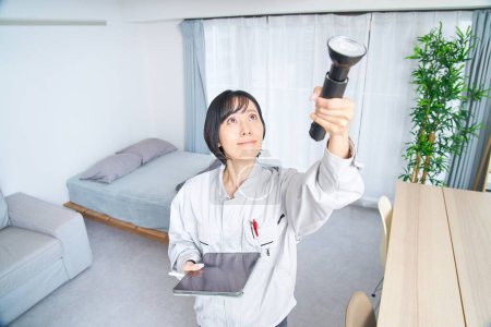Téléchargez les photos : Une femme en vêtements de travail vérifiant la chambre - en image libre de droit