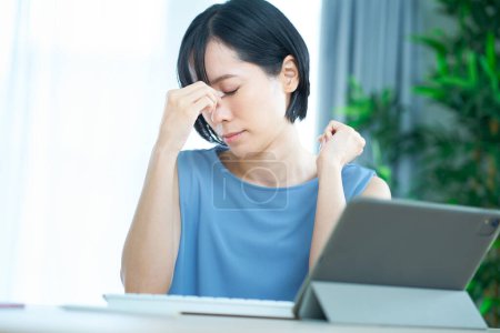 Foto de Una mujer que parece cansada delante de una computadora en la habitación - Imagen libre de derechos