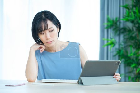 Photo for A woman touching a computer with an uneasy expression in the room - Royalty Free Image