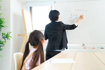 Photo for A woman in a suit teaching a child in the room - Royalty Free Image