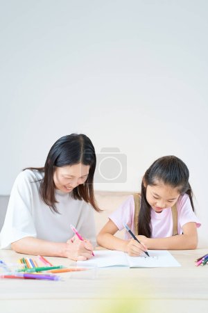 Eltern und Kind spielen und zeichnen im Zimmer