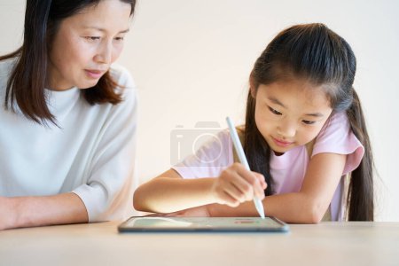 Photo for Parent and child playing with a tablet PC in the room - Royalty Free Image
