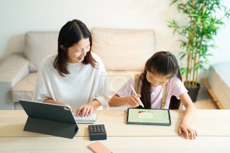 Photo for A girl playing with a woman who works using a tablet PC at home - Royalty Free Image