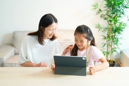 Téléchargez les photos : Parent et enfant regardant l'écran de la tablette PC avec un sourire - en image libre de droit
