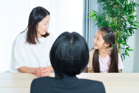 Photo for Conversation scene of a woman in a suit with a parent and child in the room - Royalty Free Image