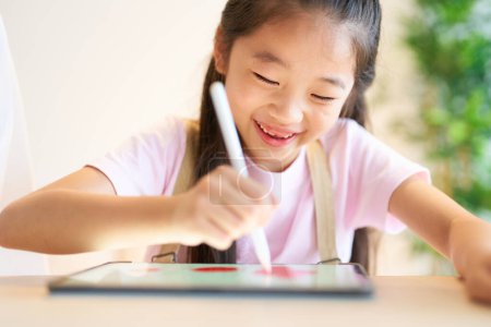 Téléchargez les photos : Enfant jouant avec tablette PC dans la chambre - en image libre de droit