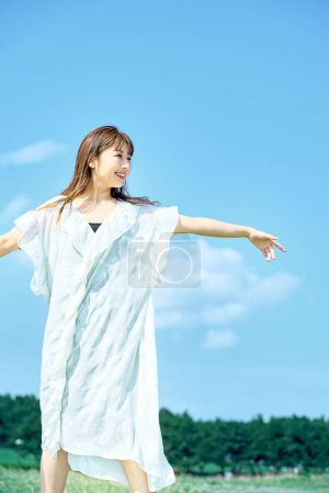 Téléchargez les photos : Une jeune femme montrant une expression détendue sous le ciel clair - en image libre de droit