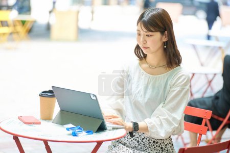 Photo for A woman operating a PC outdoors on fine day - Royalty Free Image