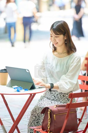 Foto de Una mujer operando un PC al aire libre en un buen día - Imagen libre de derechos