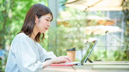 Téléchargez les photos : Une femme opérant un PC à l'extérieur le beau jour - en image libre de droit
