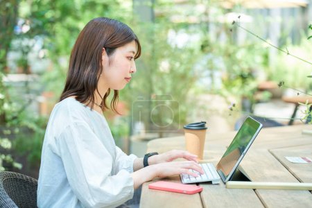 Photo for A woman operating a PC outdoors on fine day - Royalty Free Image