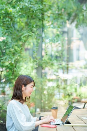 Foto de Una mujer operando un PC al aire libre en un buen día - Imagen libre de derechos
