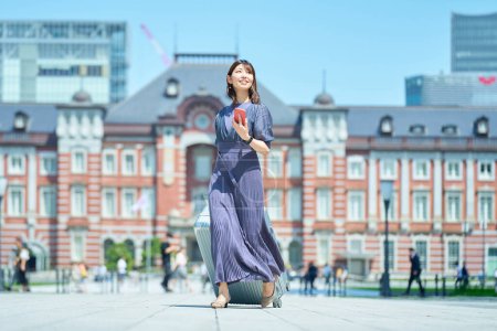 Photo for A woman walking in the city with a suitcase on fine day - Royalty Free Image