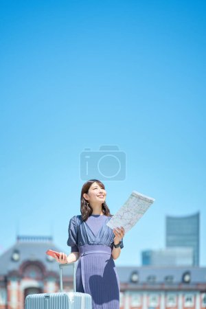 Téléchargez les photos : Une femme tenant une carte et un smartphone dans la rue - en image libre de droit