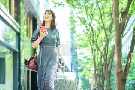 Foto de Una mujer caminando por la ciudad con una maleta en un buen día - Imagen libre de derechos