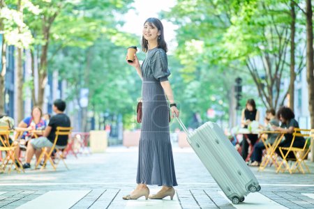 Téléchargez les photos : Une femme marchant dans la ville avec une valise le beau jour - en image libre de droit